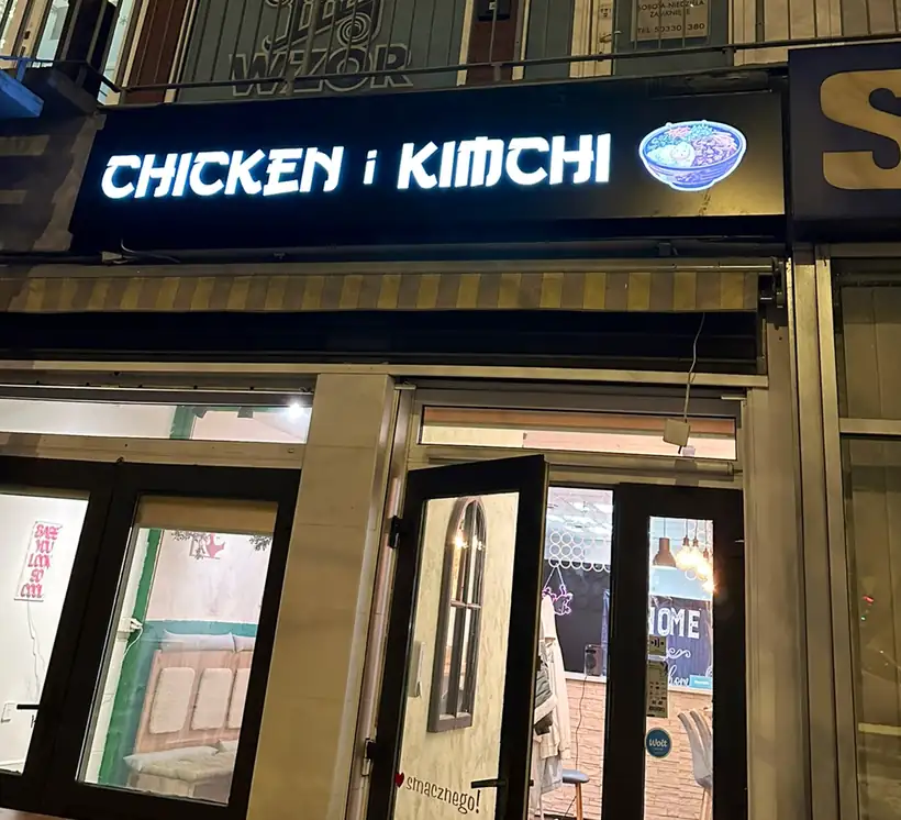 Wejście do lokalu z czarnym szyldem Chicken i Kimchi