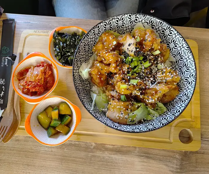 Bowl z kurczakiem i miseczkami kimchi i pikli